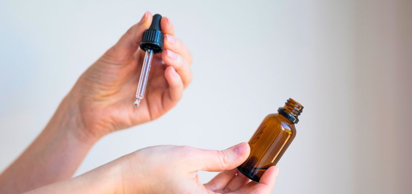 Hands carefully measuring drops while considering are essential oils safe for skin.