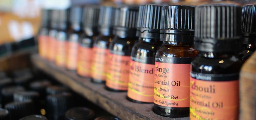 Shelf of labeled essential oils prompting research into are essential oils safe for skin.