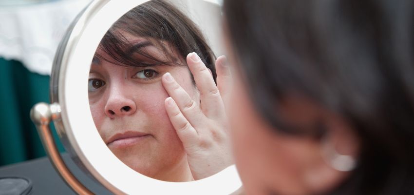 The woman checks her face in the mirror to see if she has sebaceous filaments.
