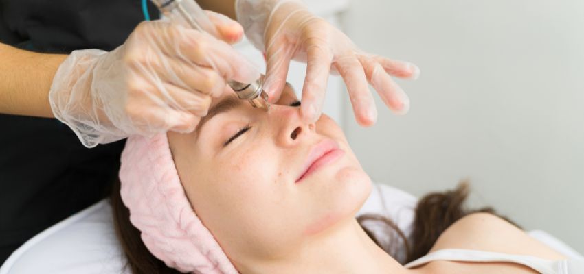 The woman is undergoing a facial treatment to remove sebaceous filaments from her face.