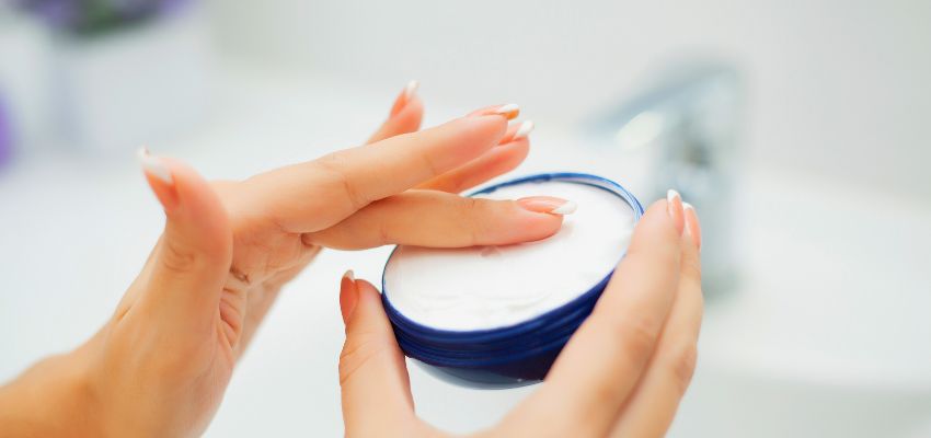 Hands scooping cream from a jar after checking it with a skincare ingredient checker.