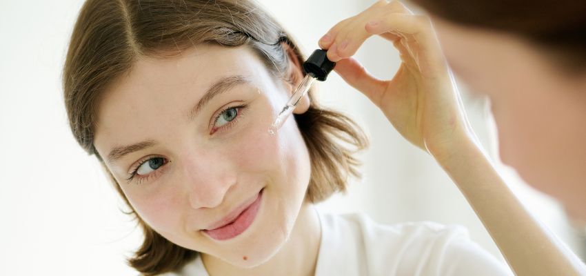 Woman applying facial serum with dropper, illustrating how tretinoin vs retinol works in skincare routines.