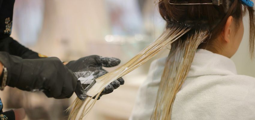 Stylist applying vibrant dye to a client’s hair while creating a modern color blocking hair look.