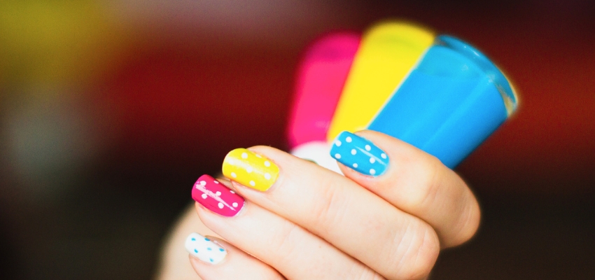 how-to-dry-gel-nail-polish-without-uv-light3 Colorful polka dot nails with bright nail polish bottles in the background, representing creative options when exploring how to dry gel nail polish without UV light.