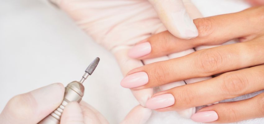 Close-up of an e-file tool being used on natural nails during the process of how to remove gel x nails safely.