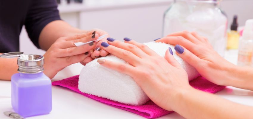 Professional nail technician demonstrating how to remove gel x nails using gentle techniques and tools in a salon setting