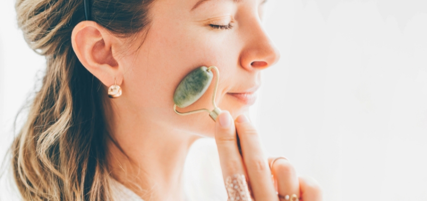 how-to-use-jade-roller2 Woman gently rolling a jade stone on her cheek, demonstrating how to use jade roller.