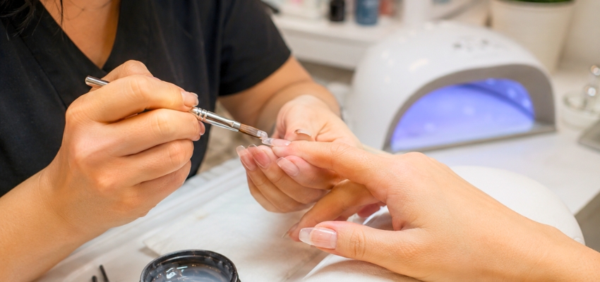 what-is-hard-gel-nails1 Nail technician carefully applying product during a session explaining what is hard gel nails.